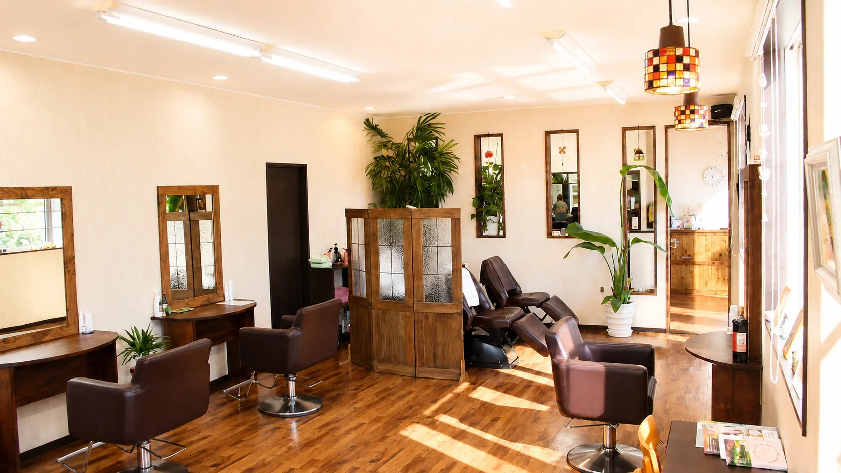 明るい日差しが差し込む伊万里市の美容室Hair Studio JAMの店内。観葉植物のある落ち着いたサロン空間。
